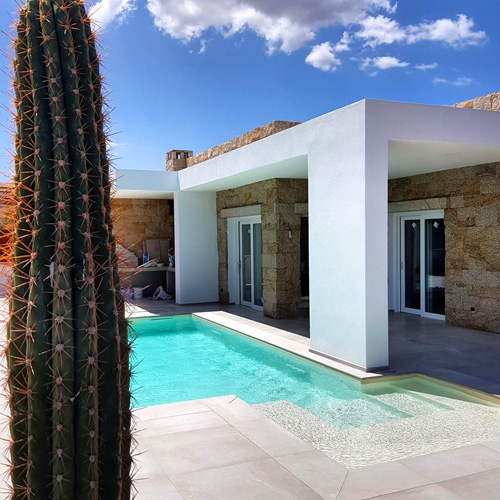 piscina lamina armada color crema en casa moderna de piedra y pavimento porcelánico