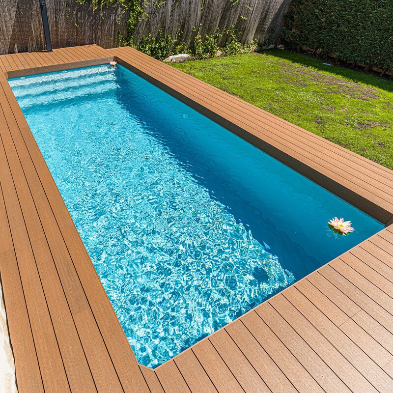 piscinas prefabricadas de poliester DTP rectangulares  con escaleras skimmer piscina y tarima de madera sintética en jardín pequeño en Madrid
