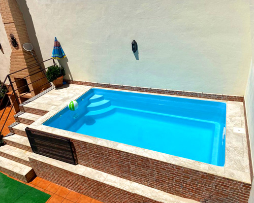 barbacoa de obra piscina de fibra azul rectangular Triana con escalera poliester de tarta para instalar en altura forrada de obra con ladrillo de obra vista