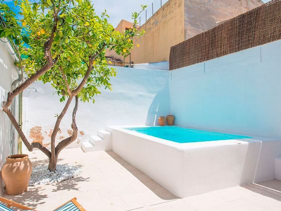 piscina de fibra elevada blanca con muro y escalera de obra barata encalada tipo piscina ibicenca en terraza pequeña