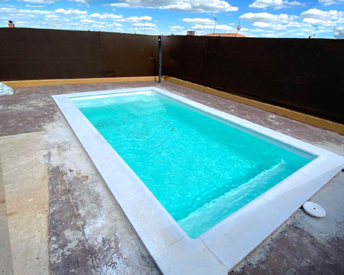 Piscina de fibra 6x3 Itálica60 en color crema y agua turquesa con banco corrido y escalera piscina