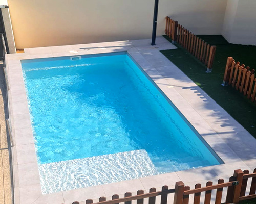 piscina 6x3 con playa de poliester Copacabana60 rodeada de valla de madera en jardin pequeño